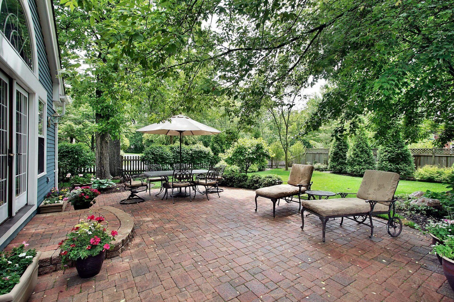 a brick patio with chairs and an umbrella