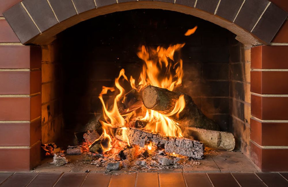Cozy brick fireplace with burning logs, vibrant flames, and warm glow, perfect for winter ambiance and relaxation.