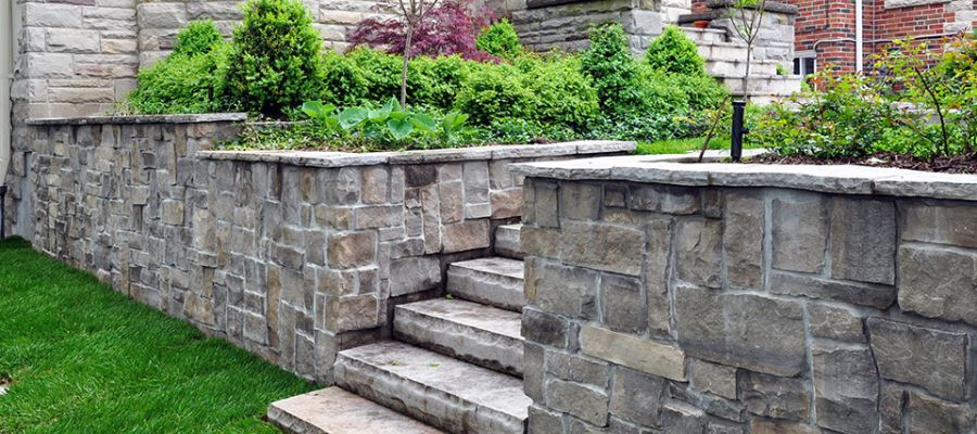 Stone retaining wall with steps and lush greenery in a landscaped garden setting, enhancing curb appeal.
