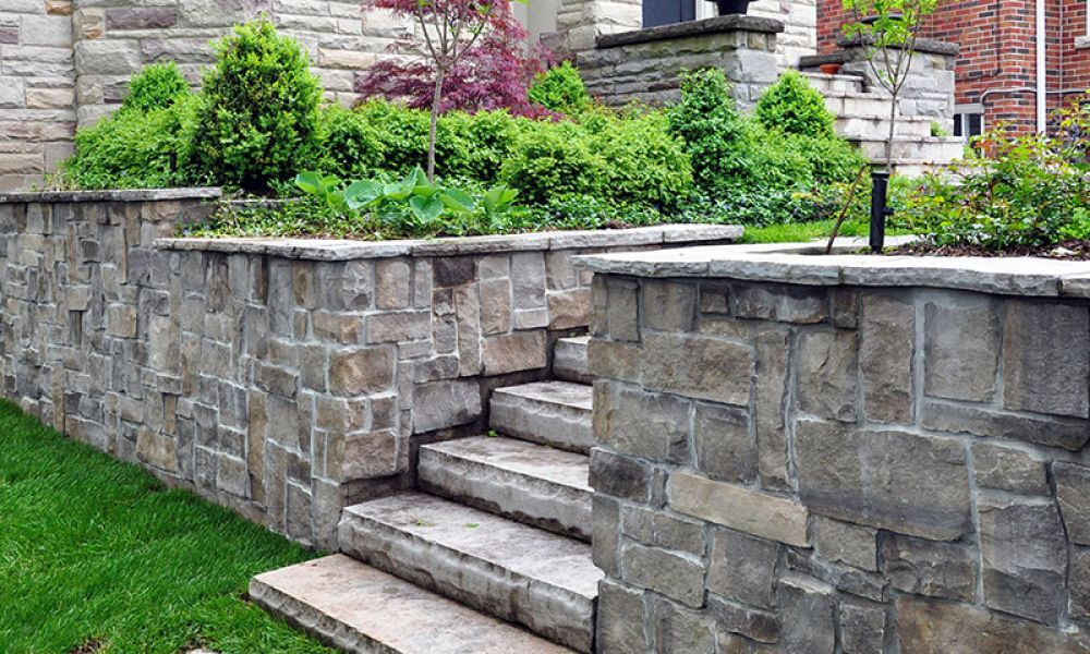 Stone retaining wall with steps and lush greenery in a landscaped garden setting, enhancing curb appeal.