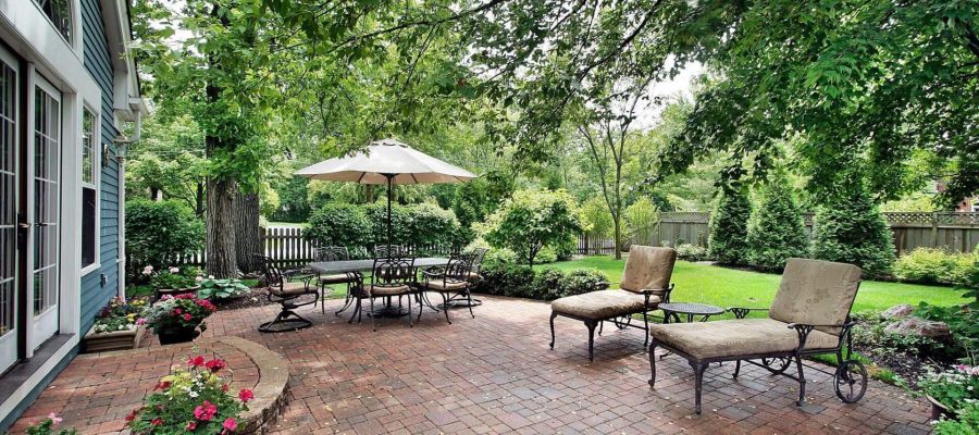 a brick patio with chairs and an umbrella
