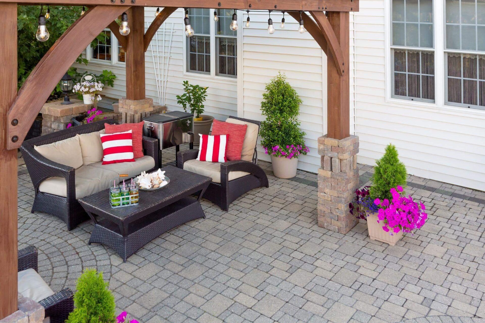 a patio with a couch, table, chairs and potted plants