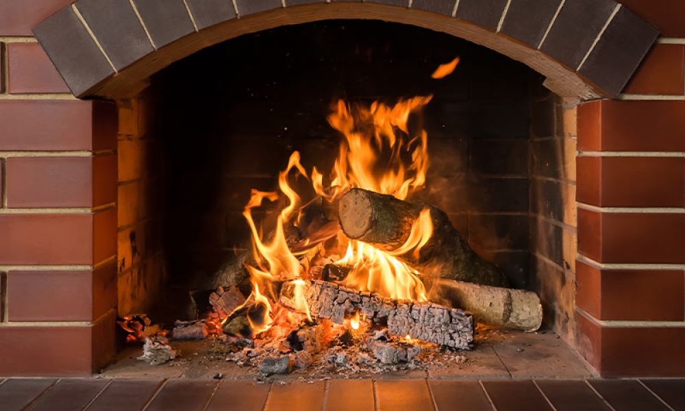 Cozy brick fireplace with burning logs, vibrant flames, and warm glow, perfect for winter ambiance and relaxation.