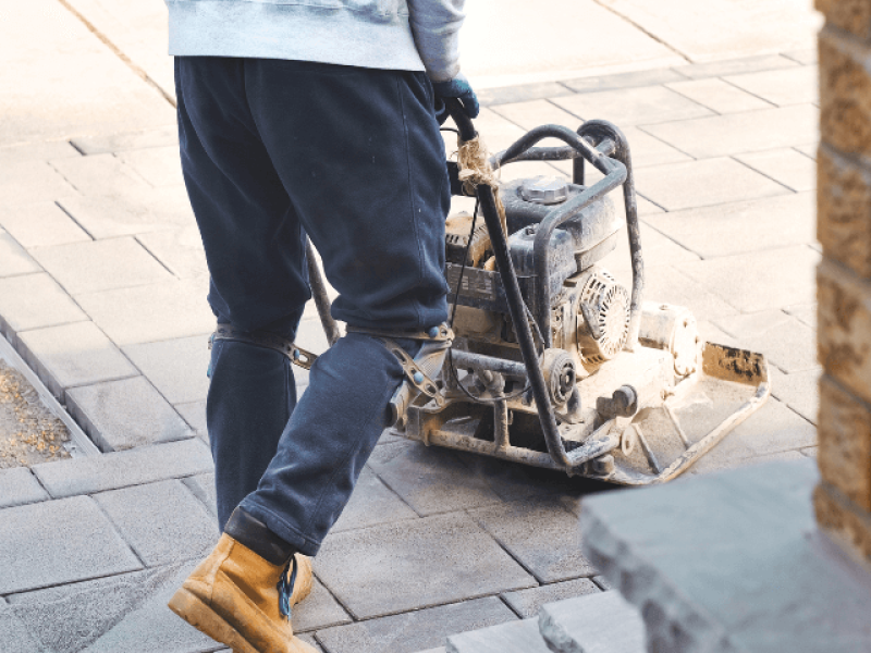 plate compactor being used on top of pavers for sand installation
