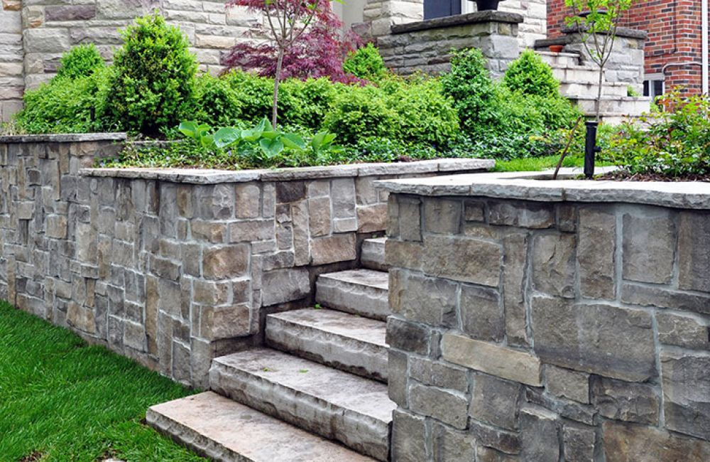 Stone retaining wall with steps and lush greenery in a landscaped garden setting, enhancing curb appeal.