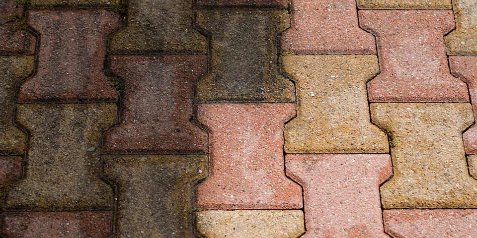 Interlocking brick pavement in red and beige hues with a worn texture, ideal for garden paths and outdoor spaces.