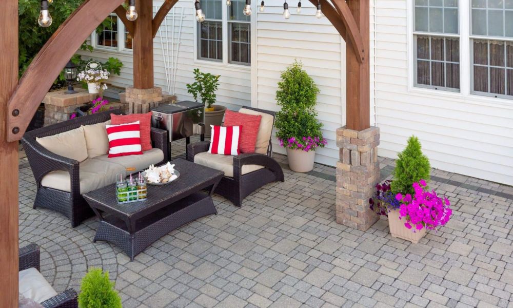 a patio with a couch, table, chairs and potted plants