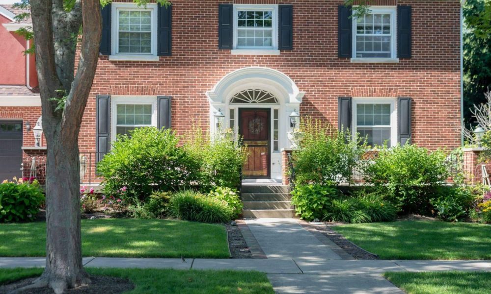 a brick house with black shutters and a red door