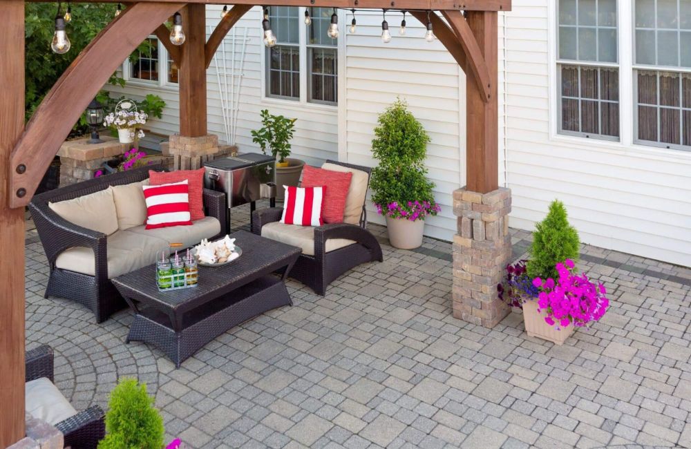 a patio with a couch, table, chairs and potted plants