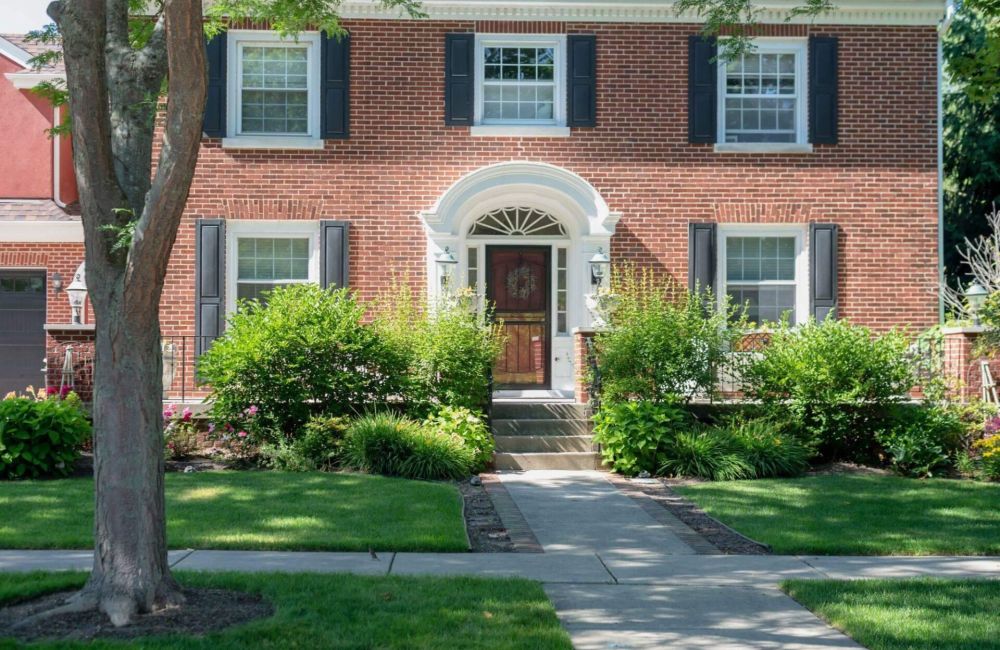 a brick house with black shutters and a red door
