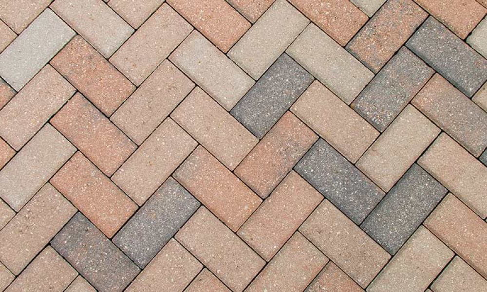 Herringbone pattern of interlocking paver bricks in earthy tones for outdoor flooring and landscaping design.