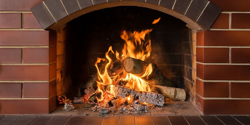 Cozy brick fireplace with burning logs, vibrant flames, and warm glow, perfect for winter ambiance and relaxation.