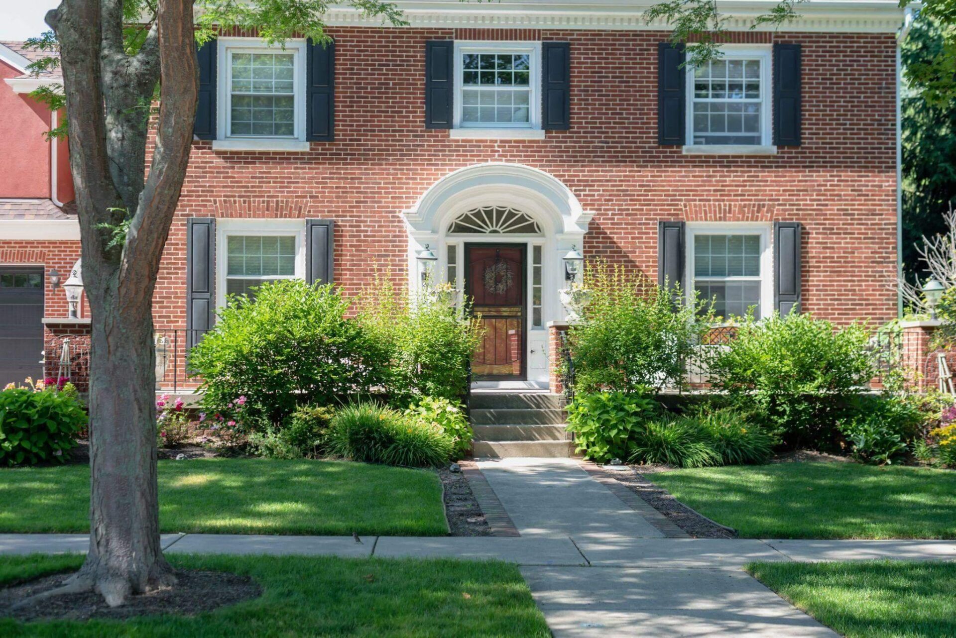 a brick house with black shutters and a red door