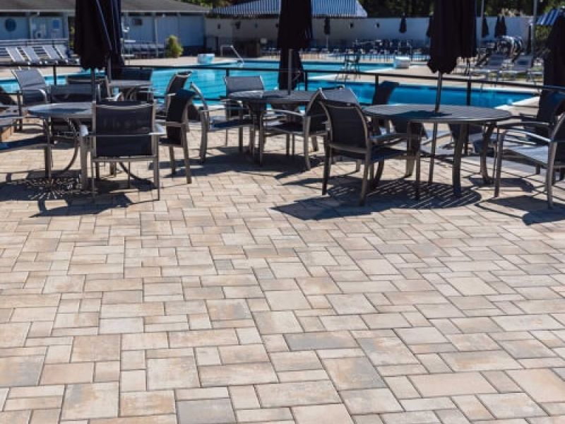 Outdoor pool area with paver patio and chairs, perfect for relaxation and social gatherings on sunny days.
