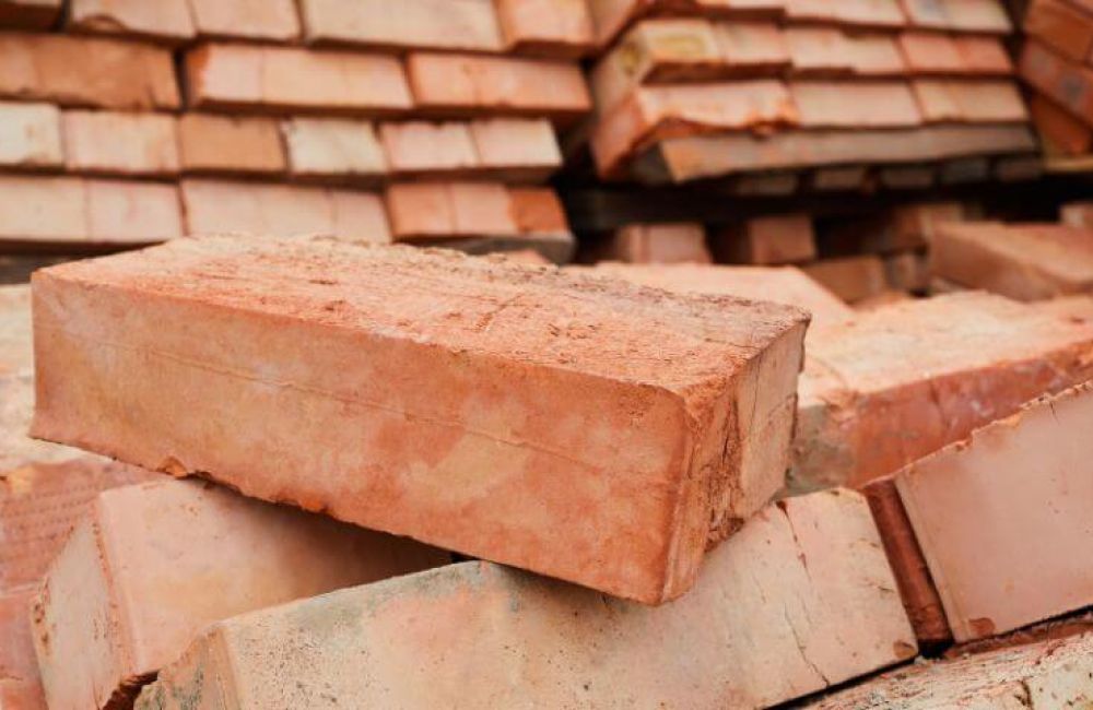 A stack of red construction bricks piled haphazardly in a construction site setting.