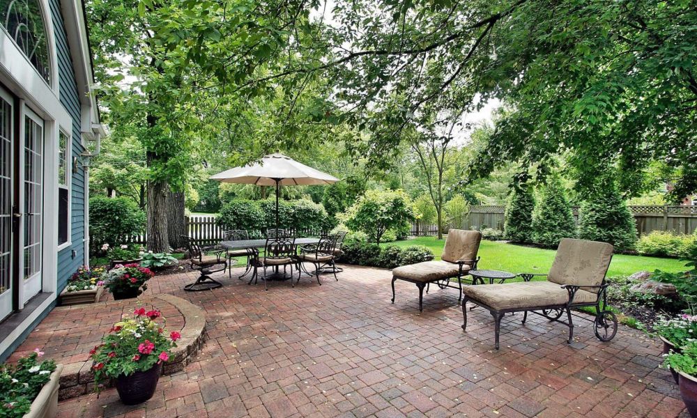 a brick patio with chairs and an umbrella