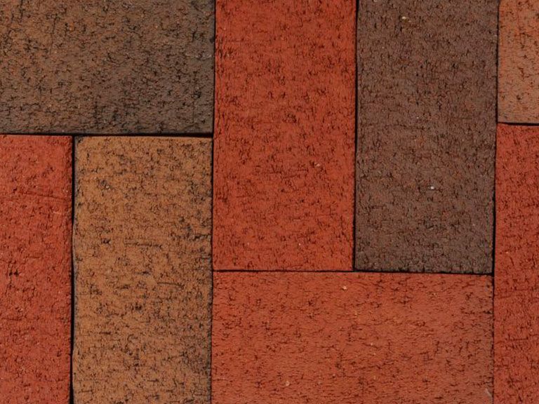 Close-up of textured, multi-toned brick wall featuring shades of red and brown in a square, interlocking pattern.
