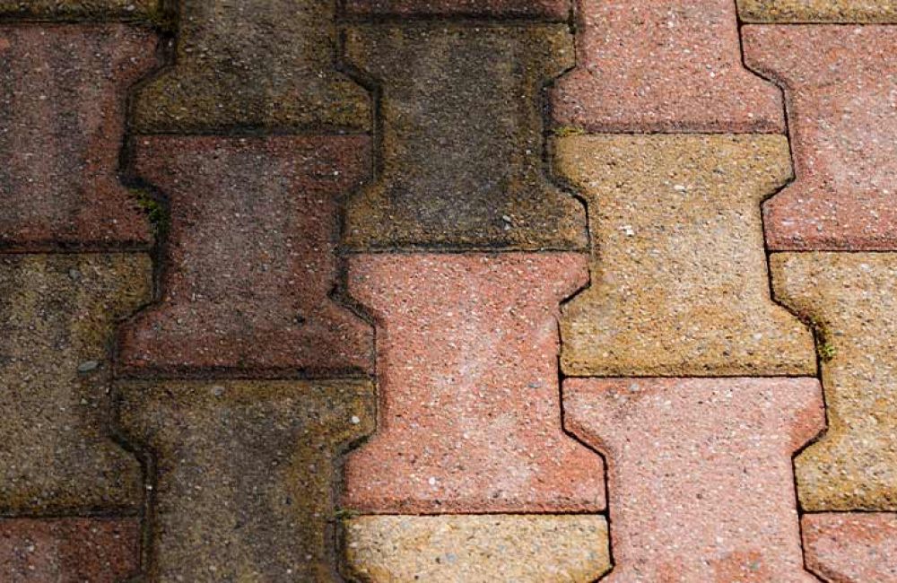 Interlocking brick pavement in red and beige hues with a worn texture, ideal for garden paths and outdoor spaces.