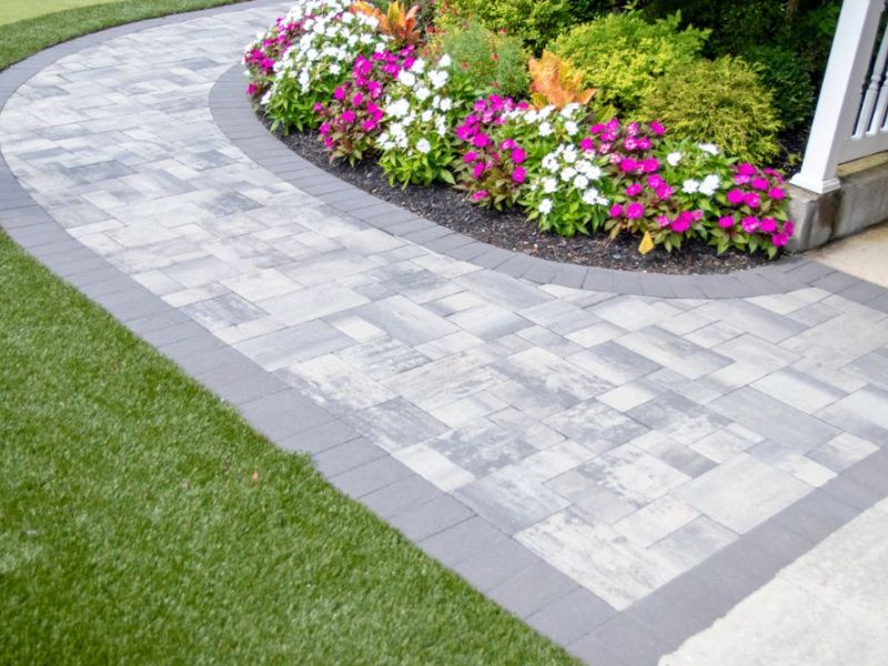 Stone pathway with blooming flowers and lush greenery enhancing a garden landscape.