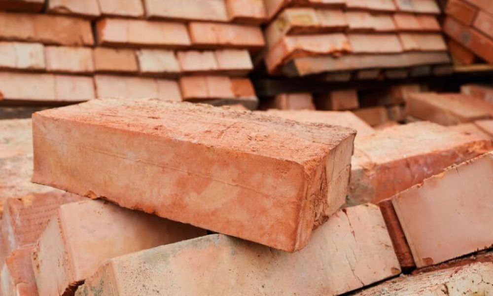 A stack of red construction bricks piled haphazardly in a construction site setting.