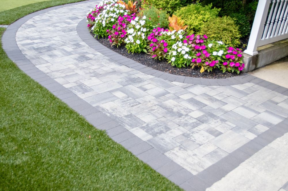 Stone pathway with blooming flowers and lush greenery enhancing a garden landscape.