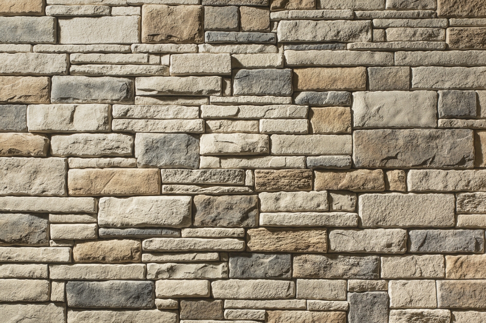Stone wall background with beige and gray bricks, showcasing a textured pattern for architectural or interior design.