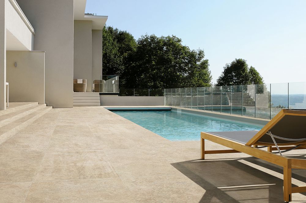 Modern villa with swimming pool, sun lounger, and glass railing offering a serene view of nature and the horizon.