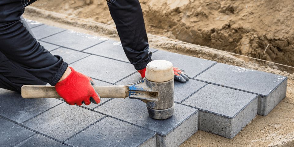 person holding mallet installing pavers
