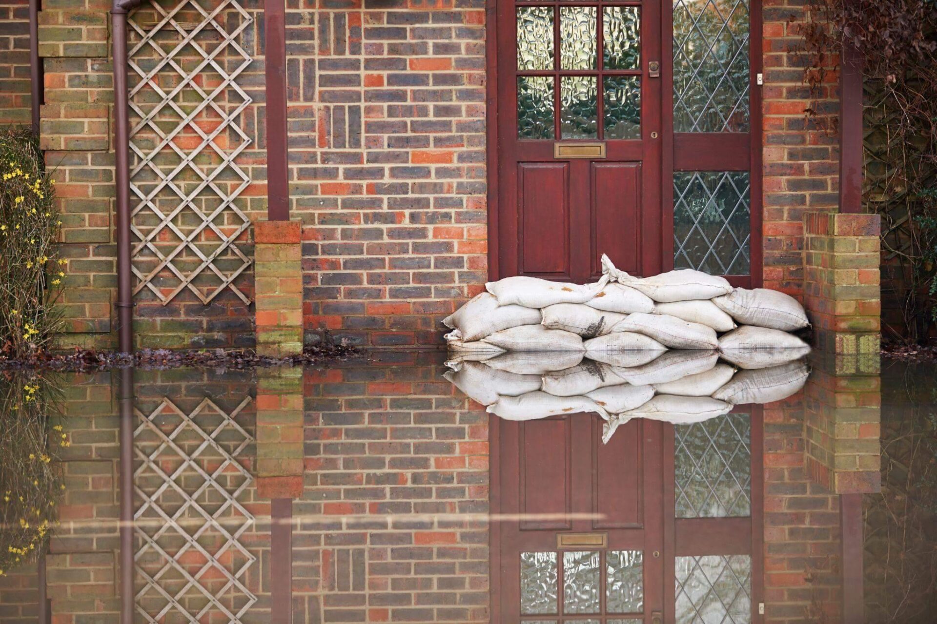 a pile of sandbags sitting in front of a brick building, there's a lot of water in front suggesting a recent flood