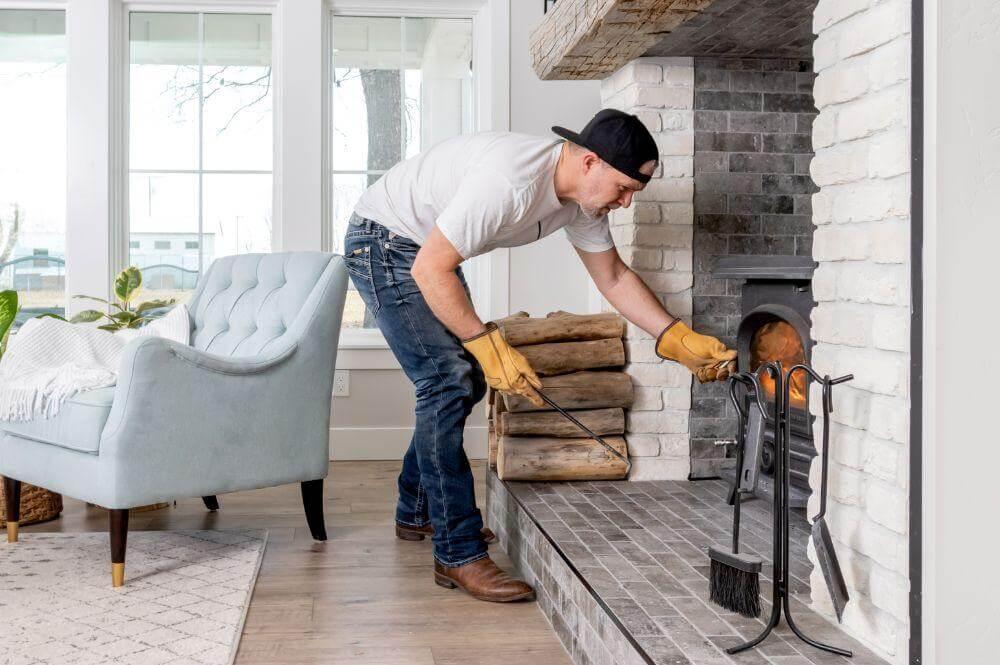Man putting wood into a brick fireplace