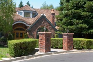 Charming brick house with tall trees and manicured bushes, showcasing a welcoming suburban curb appeal.