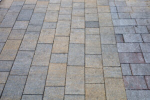 Close-up of a geometric stone tile pavement, featuring rectangular gray and beige blocks arranged in a pattern.