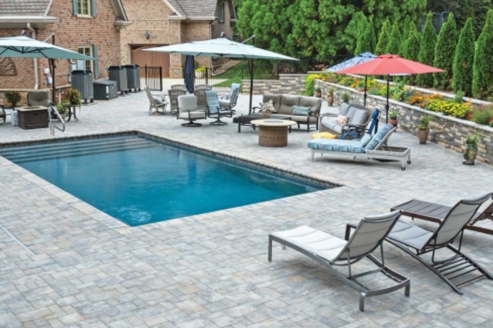 Luxurious backyard patio with pool, lounge chairs, and umbrellas for relaxation and outdoor gatherings.