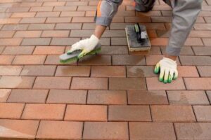 Person cleaning a brick floor with gloves