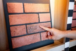 Person pointing at a brick veneer sample on a